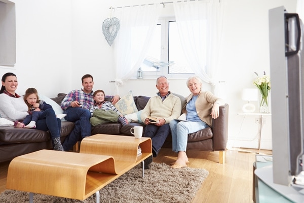 Multi Generation Family Watching TV Together In Living Room