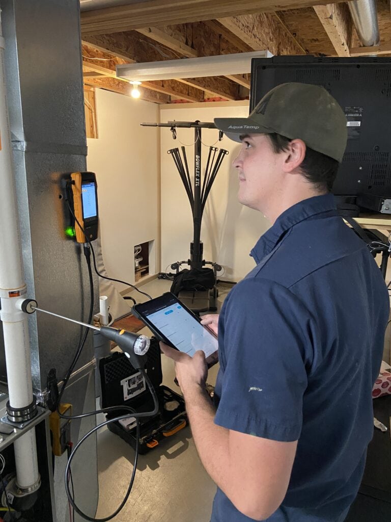 Aquatemp Service Technician, Kaelan performing a combustion analysis on a furnace in the home.