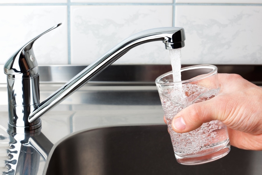 Hand holding a glass of water poured from the kitchen faucet. Concerned About High Levels of Lead In Your Water?
