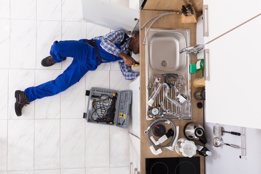 Plumber trying to fix a kitchen sink located in a big house in Warman, SK.